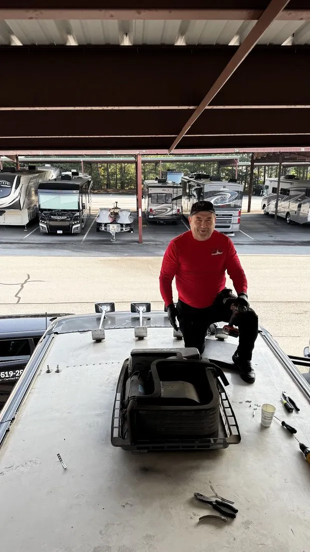 Triumphant technician servicing an RV roof unit